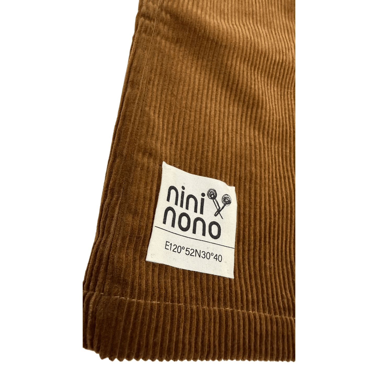 Detailed shot of the A-line skirt hem featuring a sewn-on woven fabric patch with printed brand details.