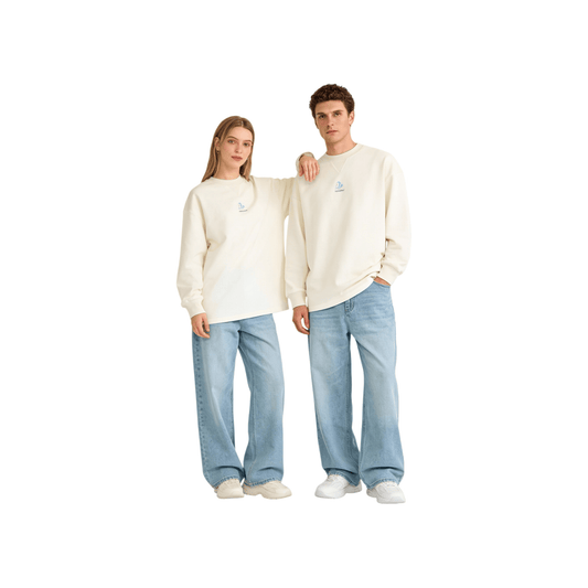 A male and female model wearing the off-white oversized long-sleeve tee with light blue jeans, demonstrating the effortless gender-neutral fit and versatile styling.
