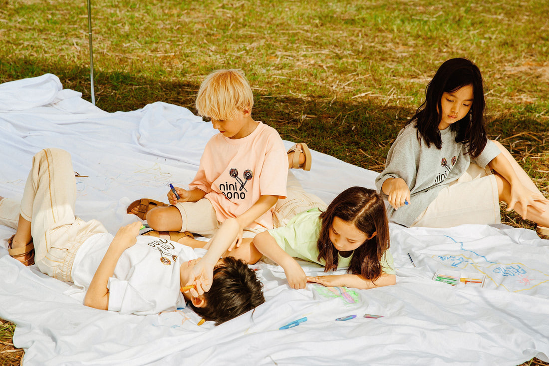 Children in unisex clothing from Ogender ninø collection playing and drawing outdoors