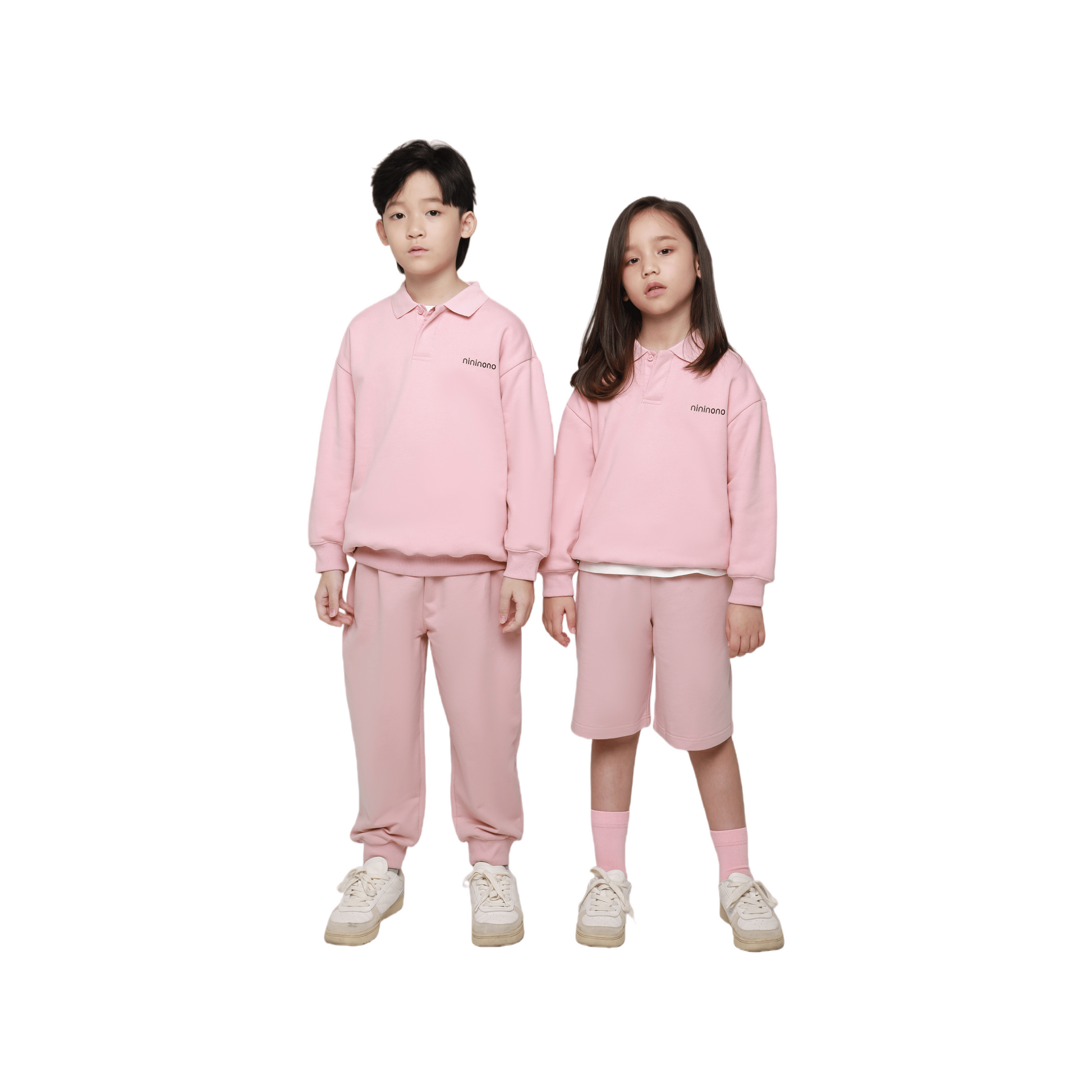 A boy and girl wearing the pink oversized polo sweatshirt and matching shorts, showcasing the relaxed gender-neutral fit.