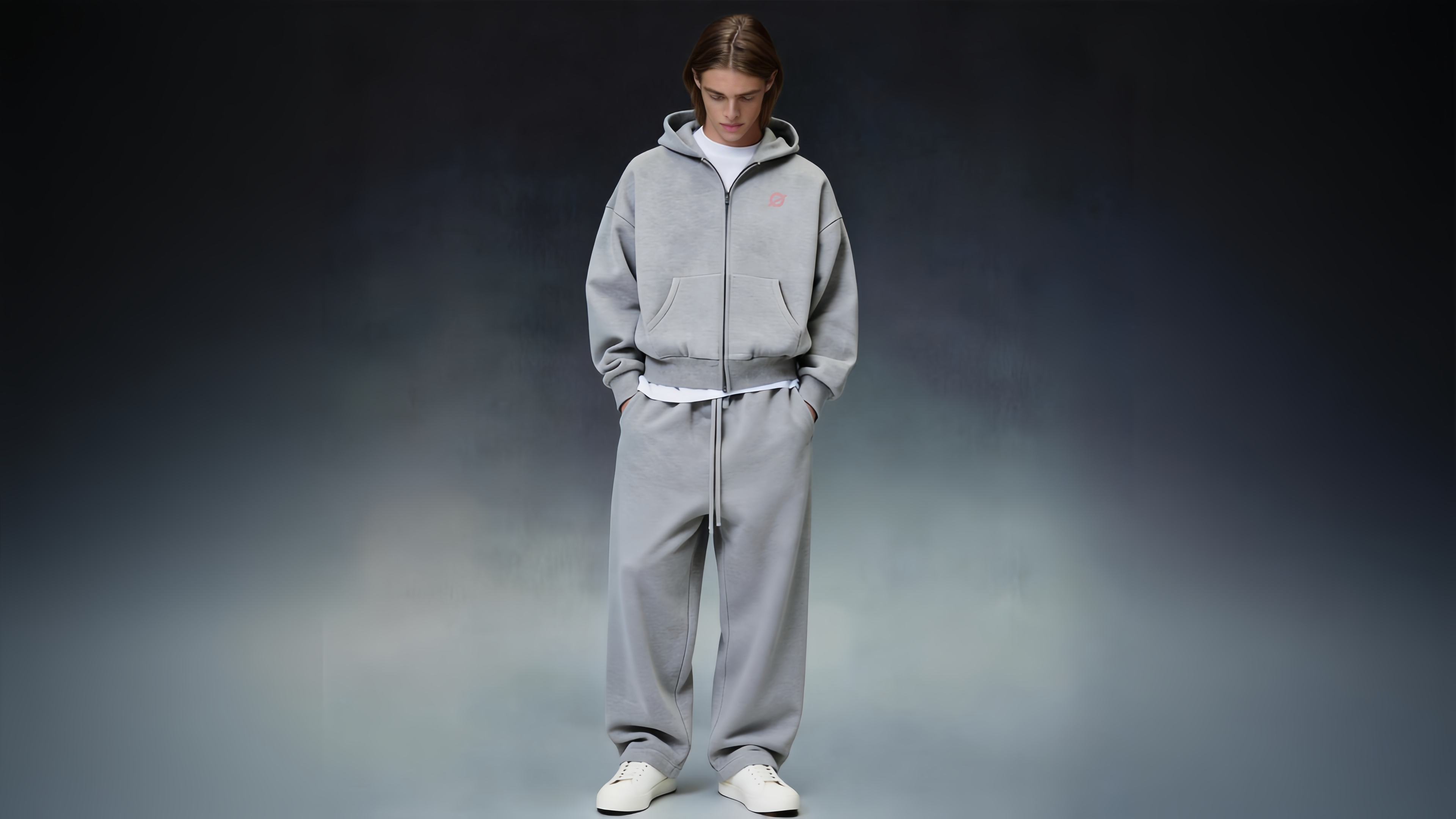 ØGENDER men's premium streetwear banner: male model in a light grey cropped zip-up hoodie layered over a white tee, paired with matching wide-leg sweatpants and white sneakers against a gradient grey background, showcasing a relaxed and minimalist Clean Fit aesthetic.