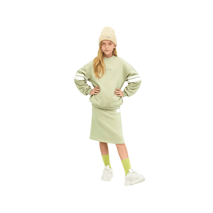 Front view of a young girl wearing the avocado green A-line sweat skirt and matching sweatshirt, highlighting the sporty printed stripes.