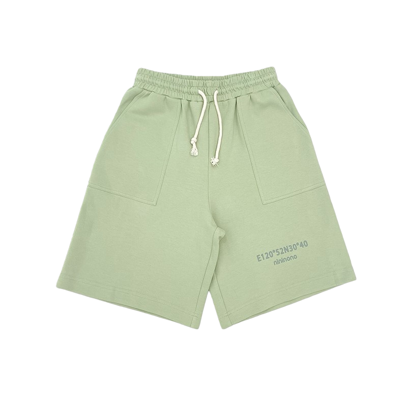 Front view of the matching sweat shorts in sage green, featuring an elastic waistband with cream drawstrings and deep side pockets.