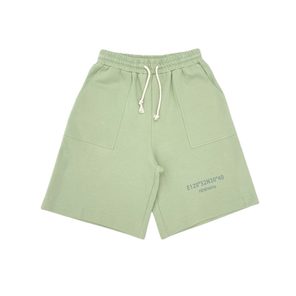 Front view of the matching sweat shorts in sage green, featuring an elastic waistband with cream drawstrings and deep side pockets.