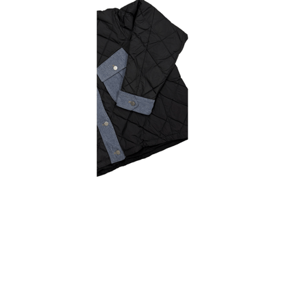 Close-up of the ninø oversized puffer jacket, highlighting the contrast blue denim fabric on the sleeve cuffs, chest pockets, and front button placket against the black diamond-quilted shell.