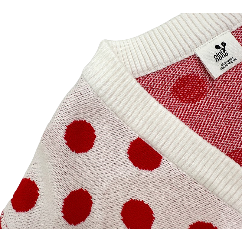 Close-up of the clean ribbed V-neckline and inner brand label on the white and red knit sweater.