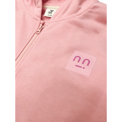 Close-up of the square logo patch on the chest of the soft pink cotton hoodie.