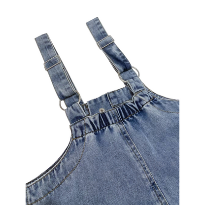 Detailed view of the adjustable metal buckles and durable stitching on the denim pinafore straps.
