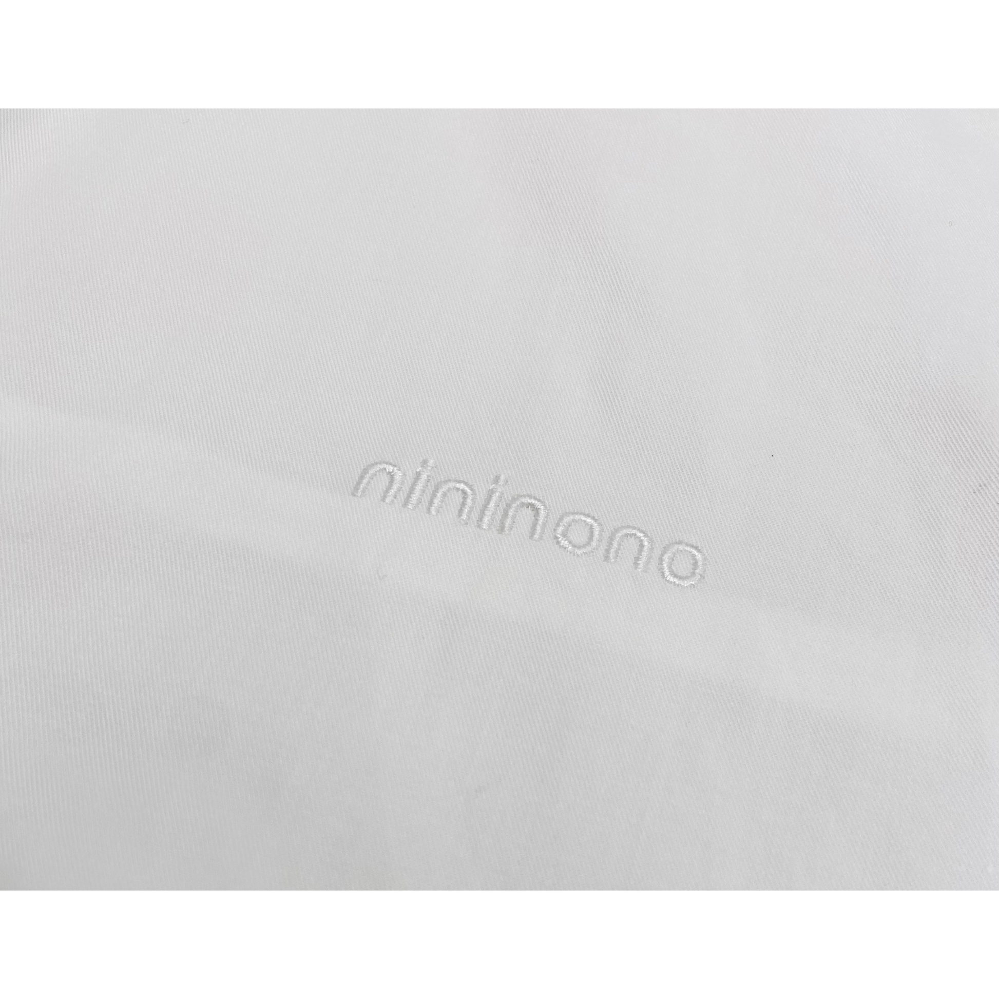 Detailed shot of the subtle tonal "nininono" embroidery on the premium white cotton surface.