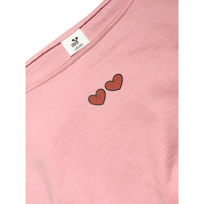 Close-up of Ogender pink sweatshirt neckline featuring dual heart graphic prints and premium brand tag.