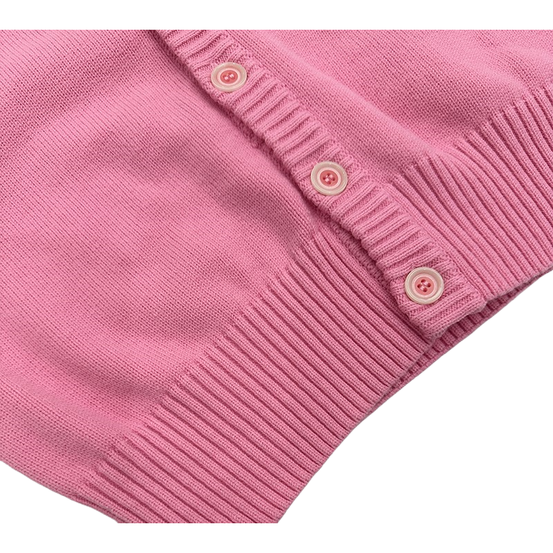 Close-up of the color-matched buttons and wide ribbed hem of the preppy knit cardigan.