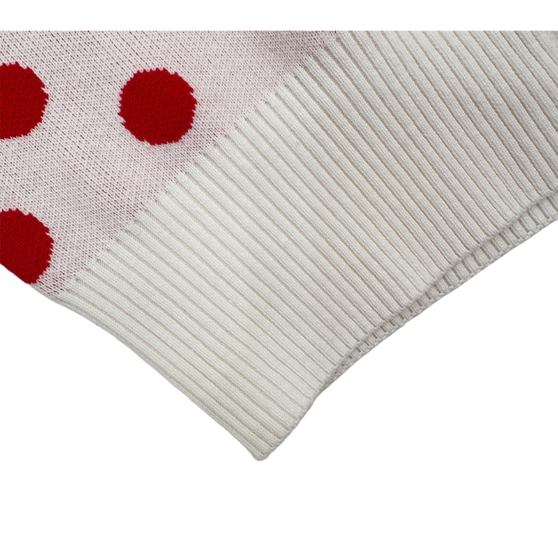 Detailed close-up of the wide ribbed hem on the white and red polka dot knit cardigan, showing the high-density knit structure and elastic recovery.