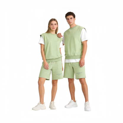 Male and female models wearing the coordinated sage green sweatshirt tank and shorts set, showcasing a modern unisex oversized fit.