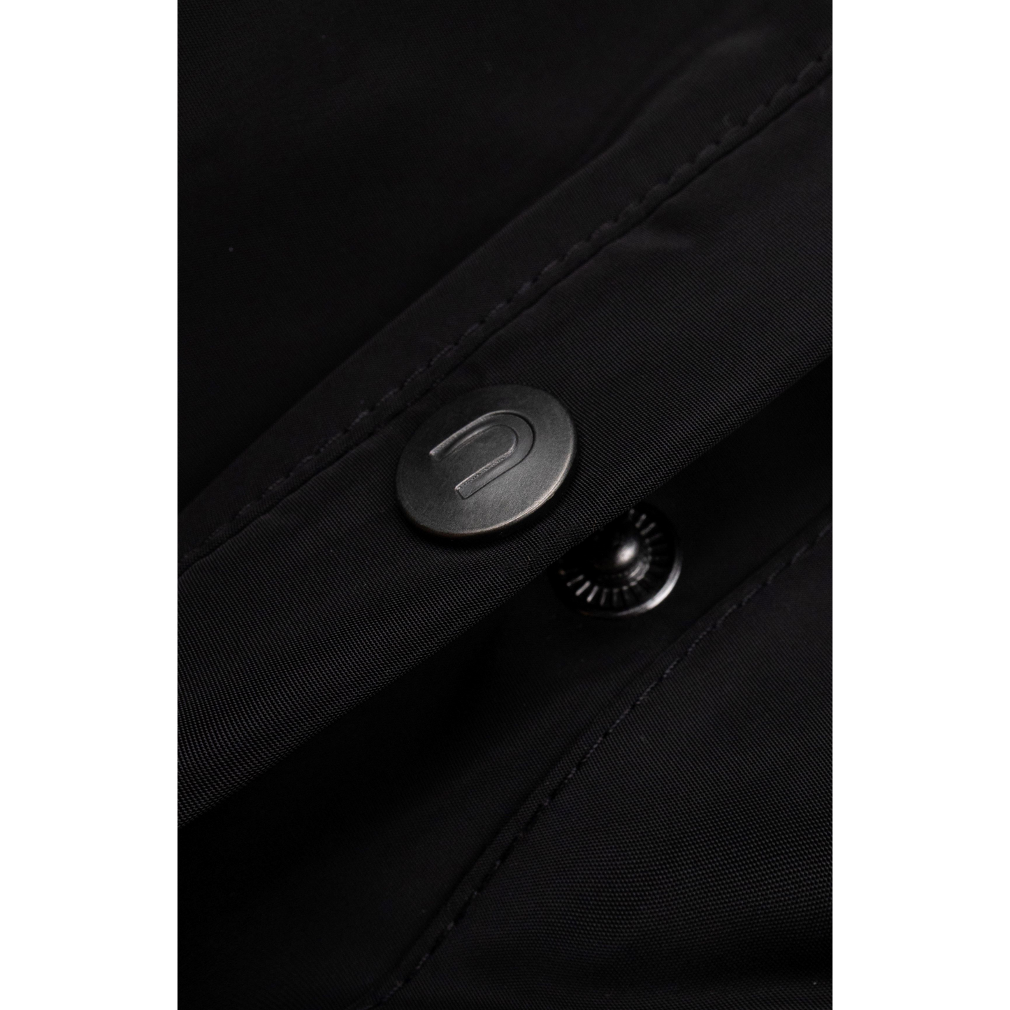 Detailed shot of the refined grey metal button on the durable water-resistant black fabric.