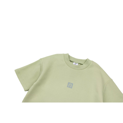 Close-up of the ribbed crewneck and the signature square 3D silicone logo printed on the chest of the avocado green dress.