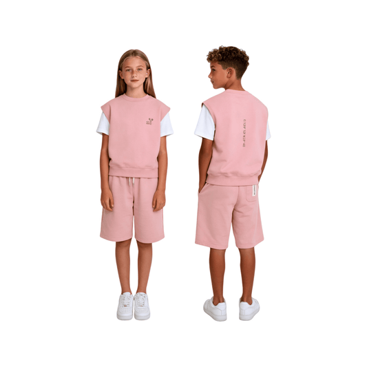 A boy and a girl showcasing the gender-neutral 100% cotton sweat shorts in light sage green and dusty pink, featuring a relaxed mid-length fit and minimalist streetwear aesthetic.