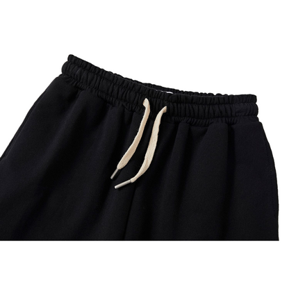 Detailed view of the elastic waistband on the kids' black joggers, featuring a high-quality ribbed texture and adjustable cream-colored drawstrings for a comfortable fit.