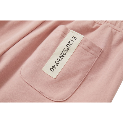 Detailed view of the back pocket on the shorts, featuring the signature sewn-on woven label with industrial-style coordinate text 'E120°52N30°40' and the 'nininono' brand logo.