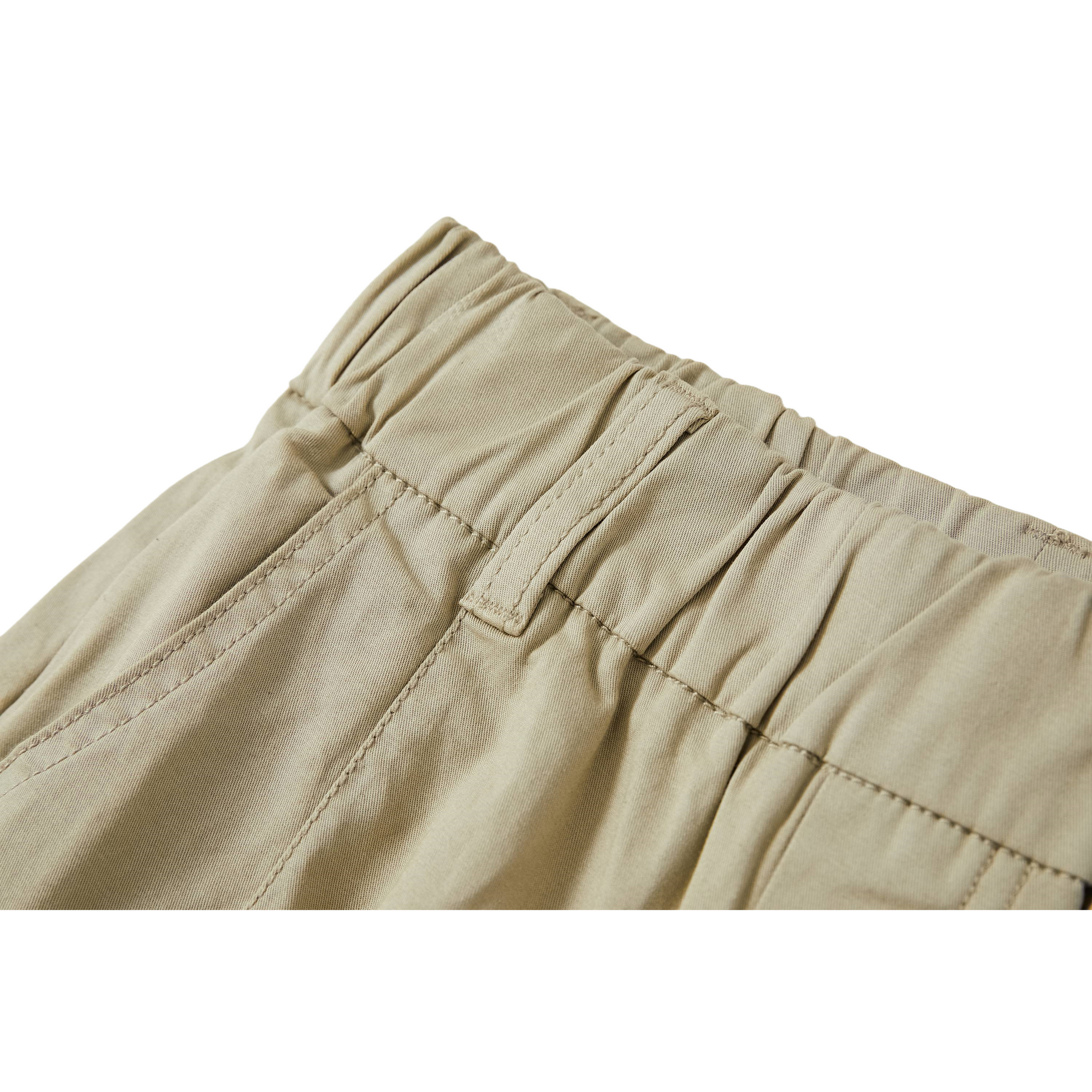 Detailed view of the comfortable elasticated waistband and clean front pleats on sage green cotton pants.