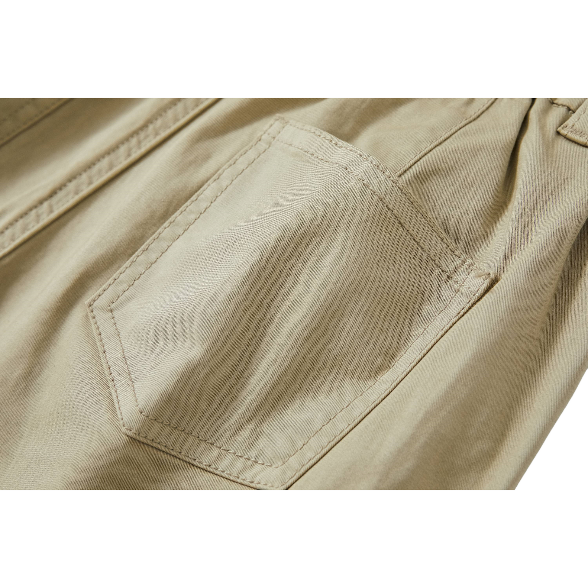 Close-up of the reinforced back pocket on light green trousers with tonal stitching.