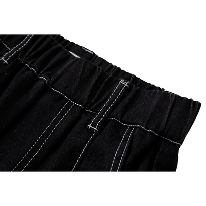 Detailed view of the elasticated waistband and front pleat construction on black denim jeans.