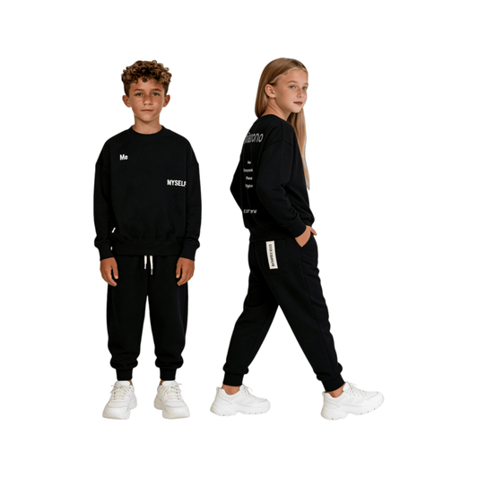 Unisex kids' streetwear styling featuring the jet black 100% cotton joggers and matching sweatshirt, showcasing the relaxed fit and signature sewn-on woven label on the back pocket.