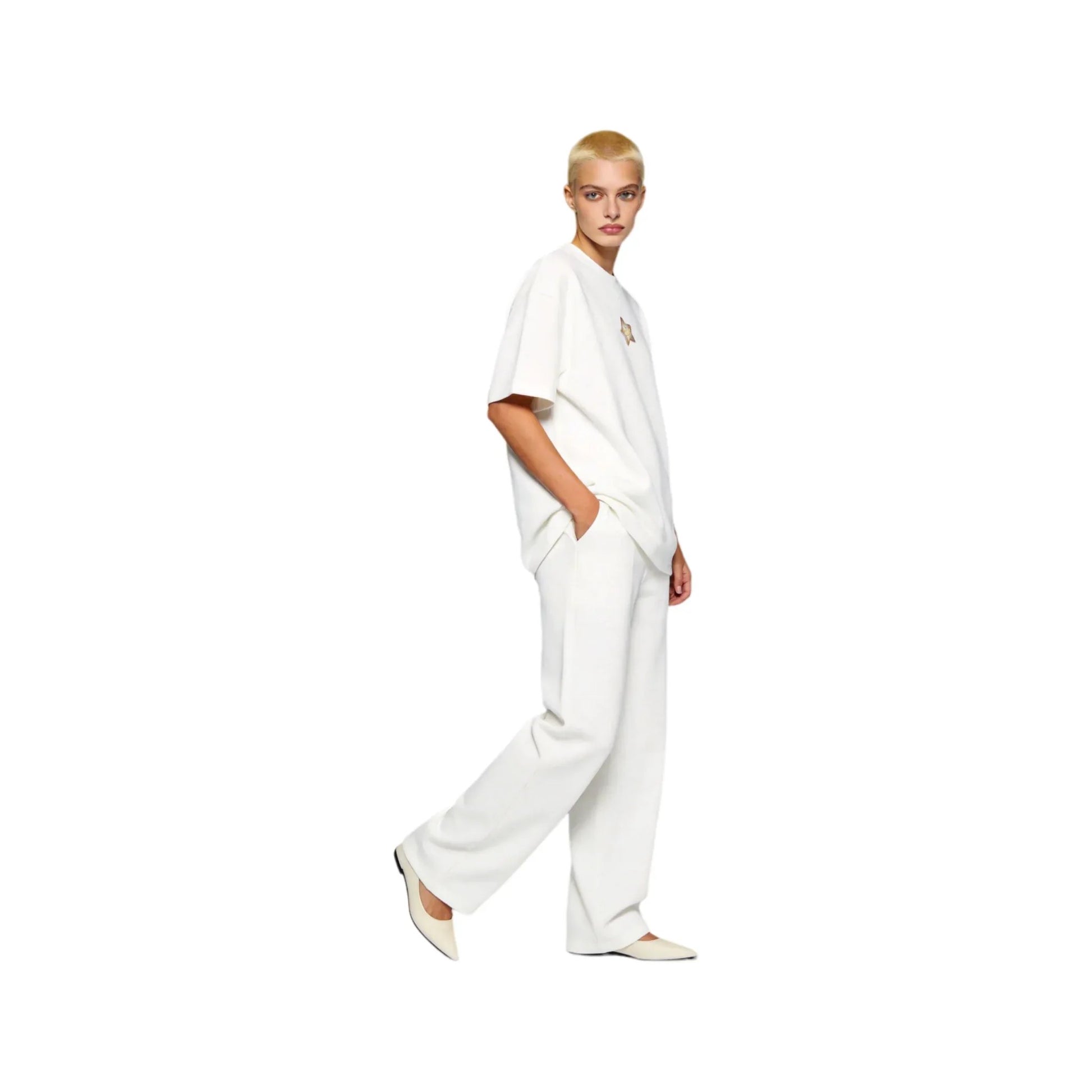 Side profile shot of a buzz-cut female model in Ogender white 240 GSM starfish tee and white pants. Highlights the relaxed dropped shoulder silhouette and the playful starfish graphic on the front