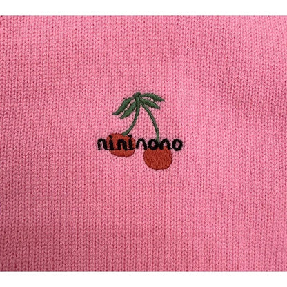 Close-up of high-density red cherry embroidery on the soft pink knit sweater.