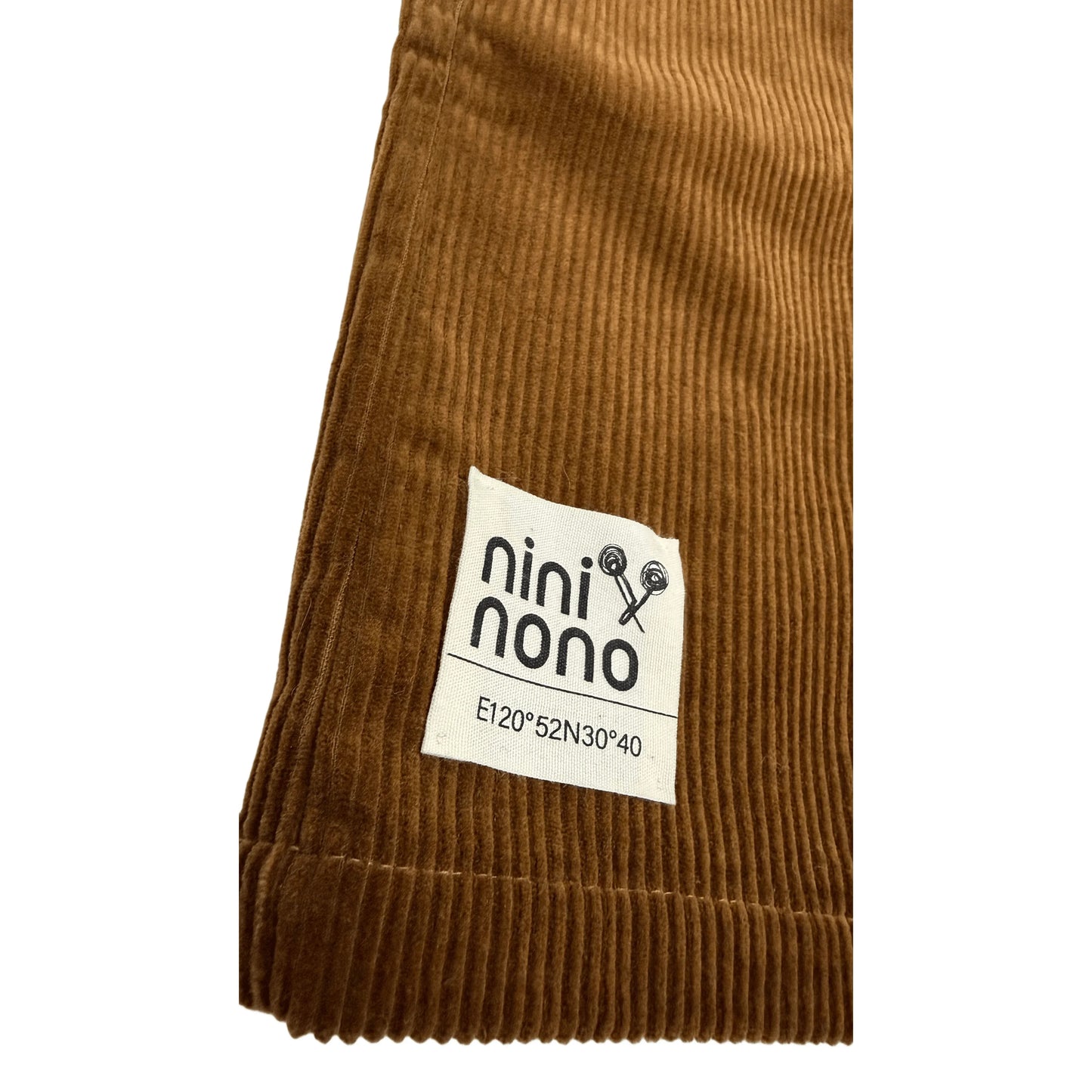 Close-up of the signature woven brand patch at the hem of the corduroy skirt.
