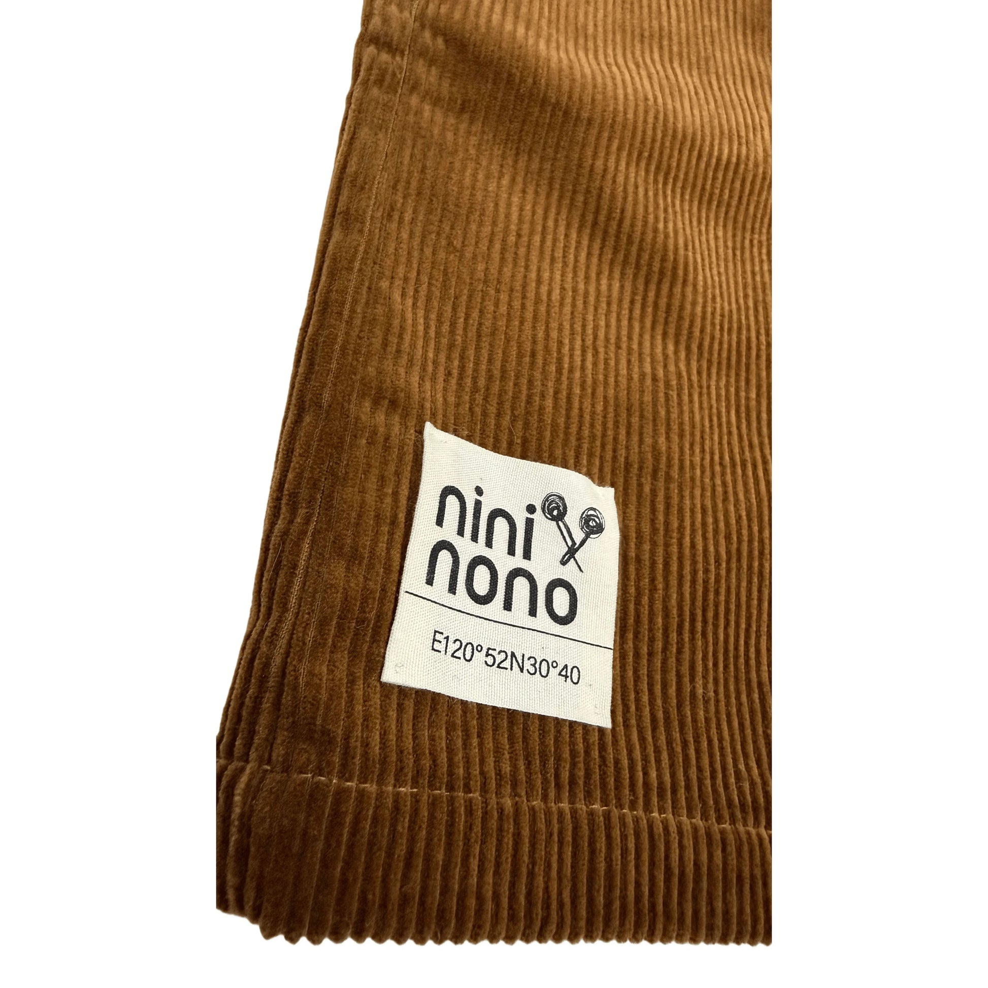 Close-up of the signature woven brand patch at the hem of the corduroy skirt.