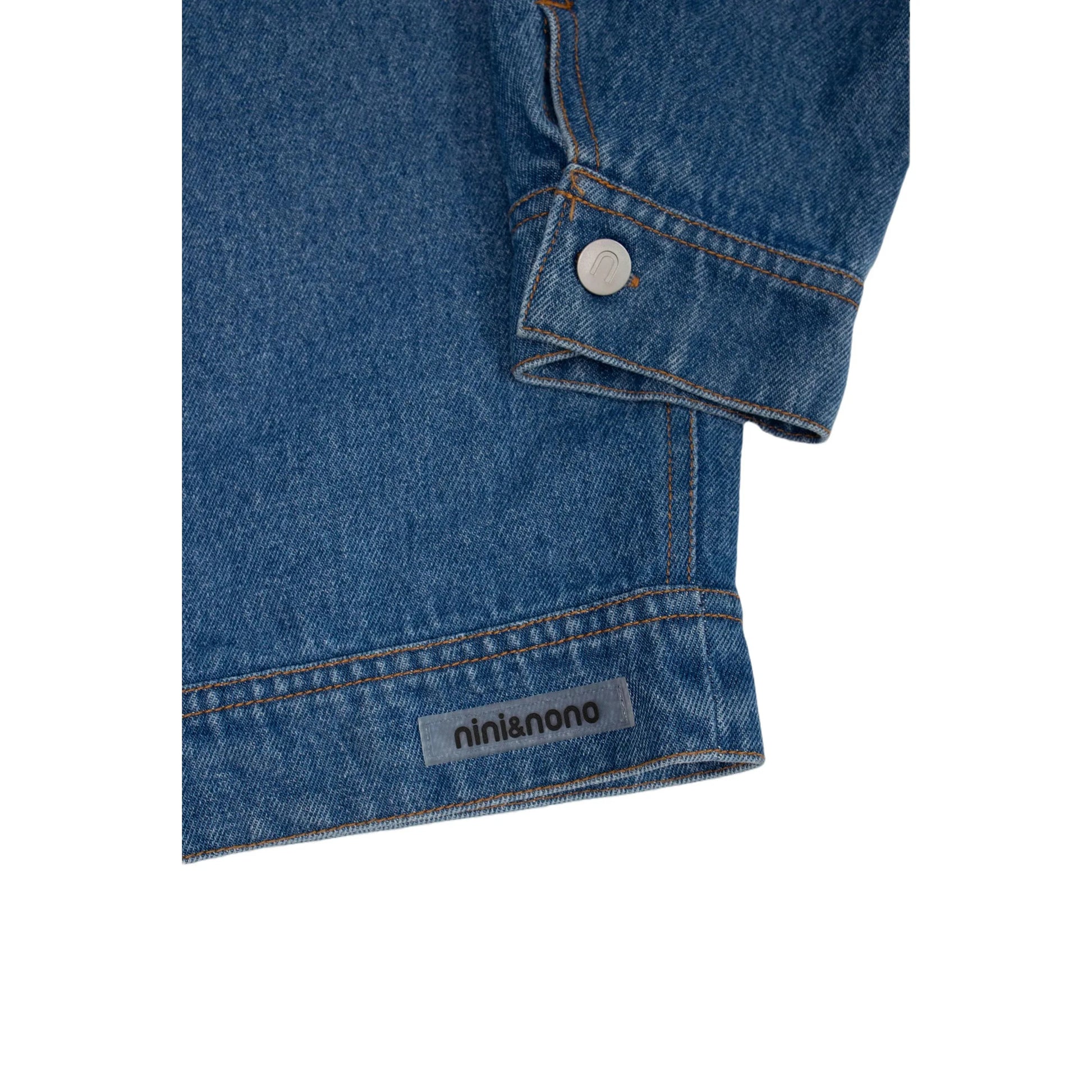 Close-up of the transparent nini&nono silicone label on the hem of the blue denim jacket.
