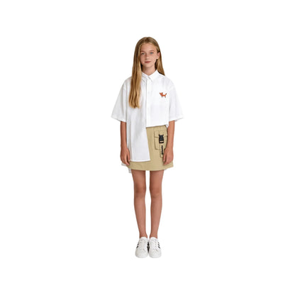 A girl modeling the khaki cargo skirt paired with a white oversized shirt.