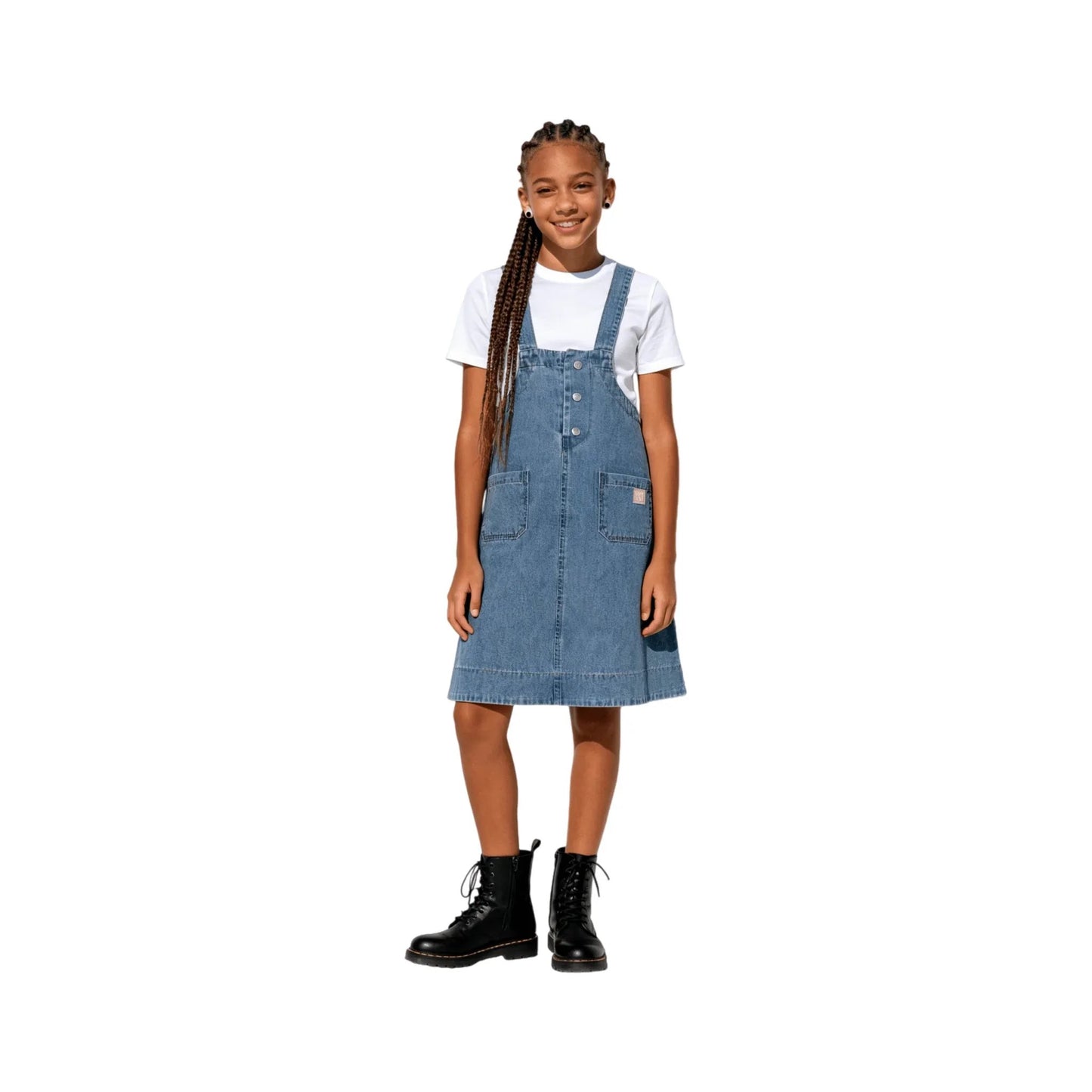 A young girl modeling the indigo denim pinafore dress, showing the waist pocket placement.