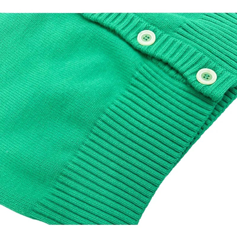 Close-up of the wide ribbed hem and color-matched industrial buttons on the green knit cardigan.