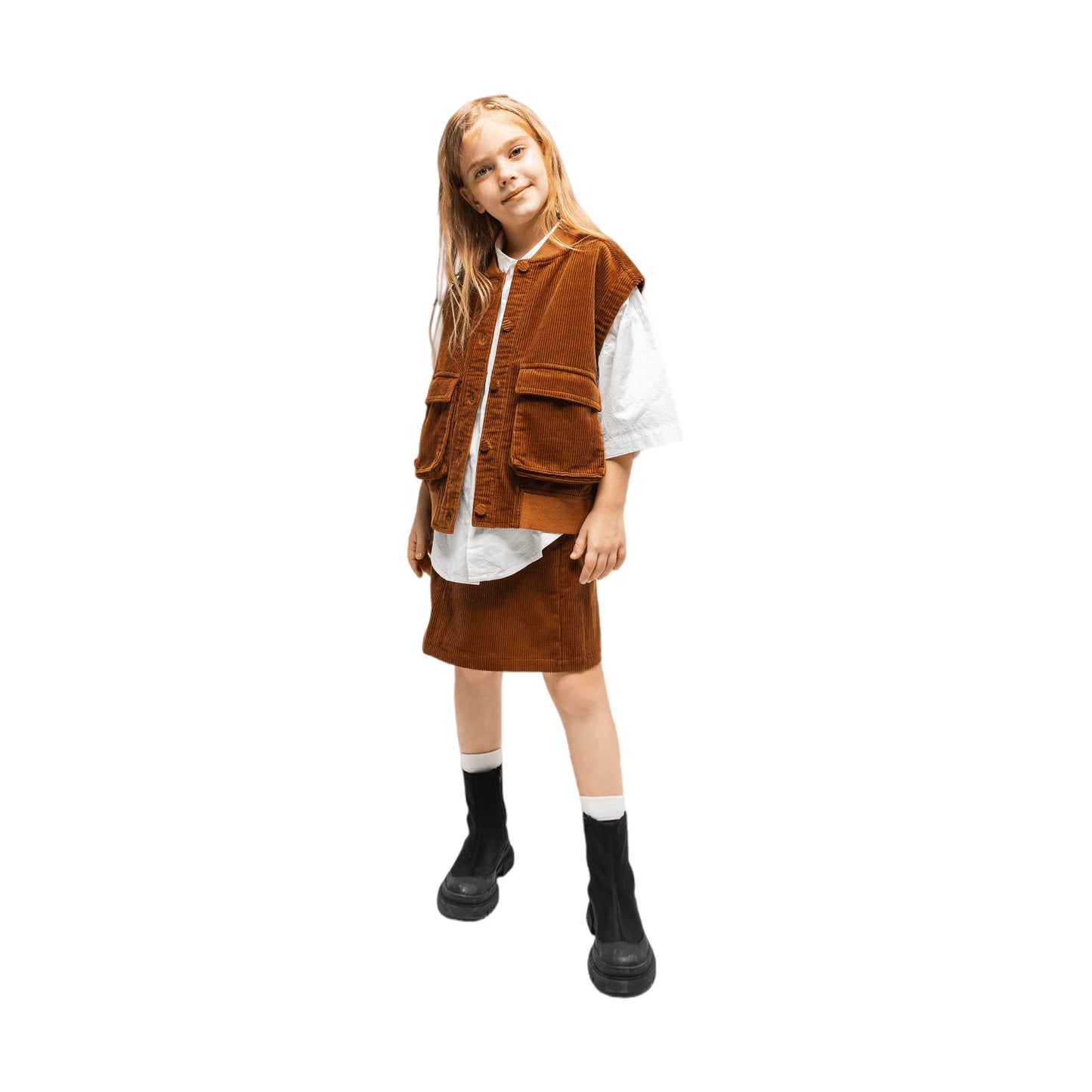 A girl modeling the caramel corduroy utility vest and matching A-line skirt with a white shirt.