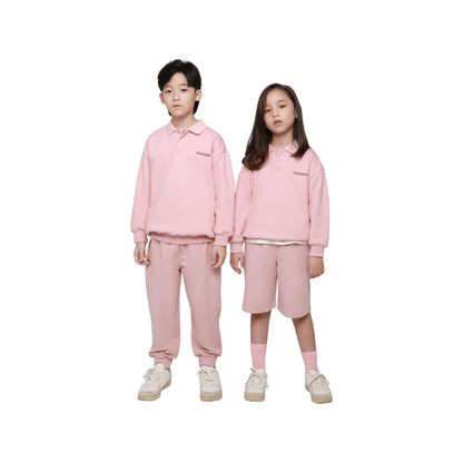 Two junior models wearing Ogender pink oversized polo sweatshirts and matching sweatpants, showcasing gender-neutral style.