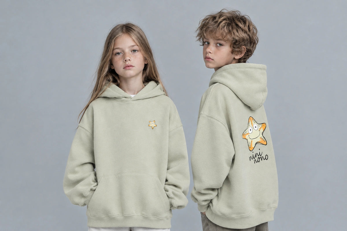 Russian girl and boy wearing oversized sage green kids' hoodies with starfish graphics on the front and back.