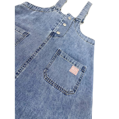 Close-up of the pink smiley embroidery on the left side pocket of the indigo denim dress.