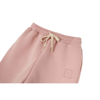 Detailed shot of the stitched smiley patch and the elasticated waistband with cream drawstrings.
