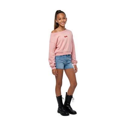 Full-body shot of a girl model wearing the pink cropped sweatshirt, styled for a high-street urban look.