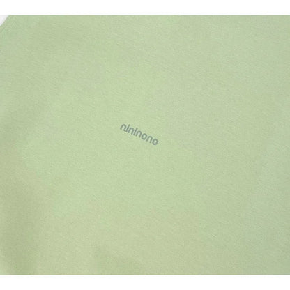 Close-up of the raised 3D silicone "nininono" graphic on the Sage Green tank.