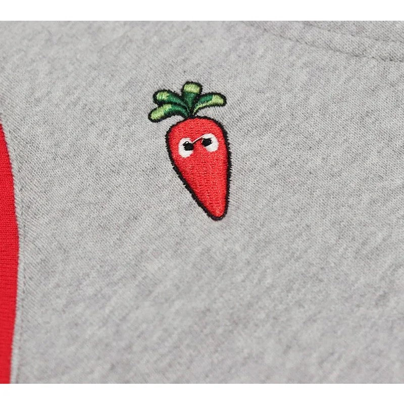 Detailed shot of the vibrant high-density carrot embroidery on the grey cotton fabric.