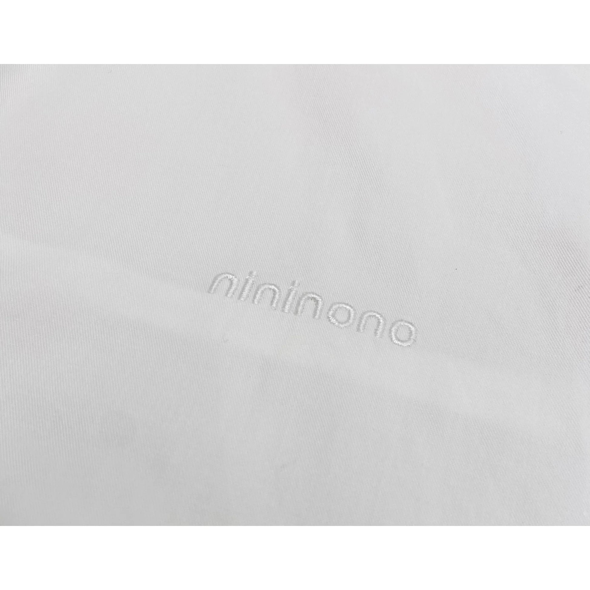 Detailed shot of the subtle white "nininono" embroidery on the left chest of the white shirt.